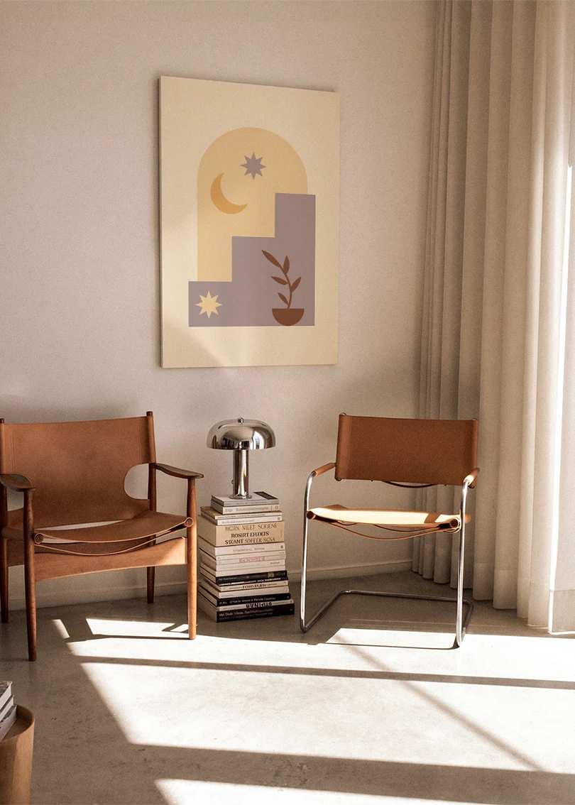 Akustikbillede med måne og stjerner ved trapper med en plante, ophængt over en brun lænestol ved vinduet