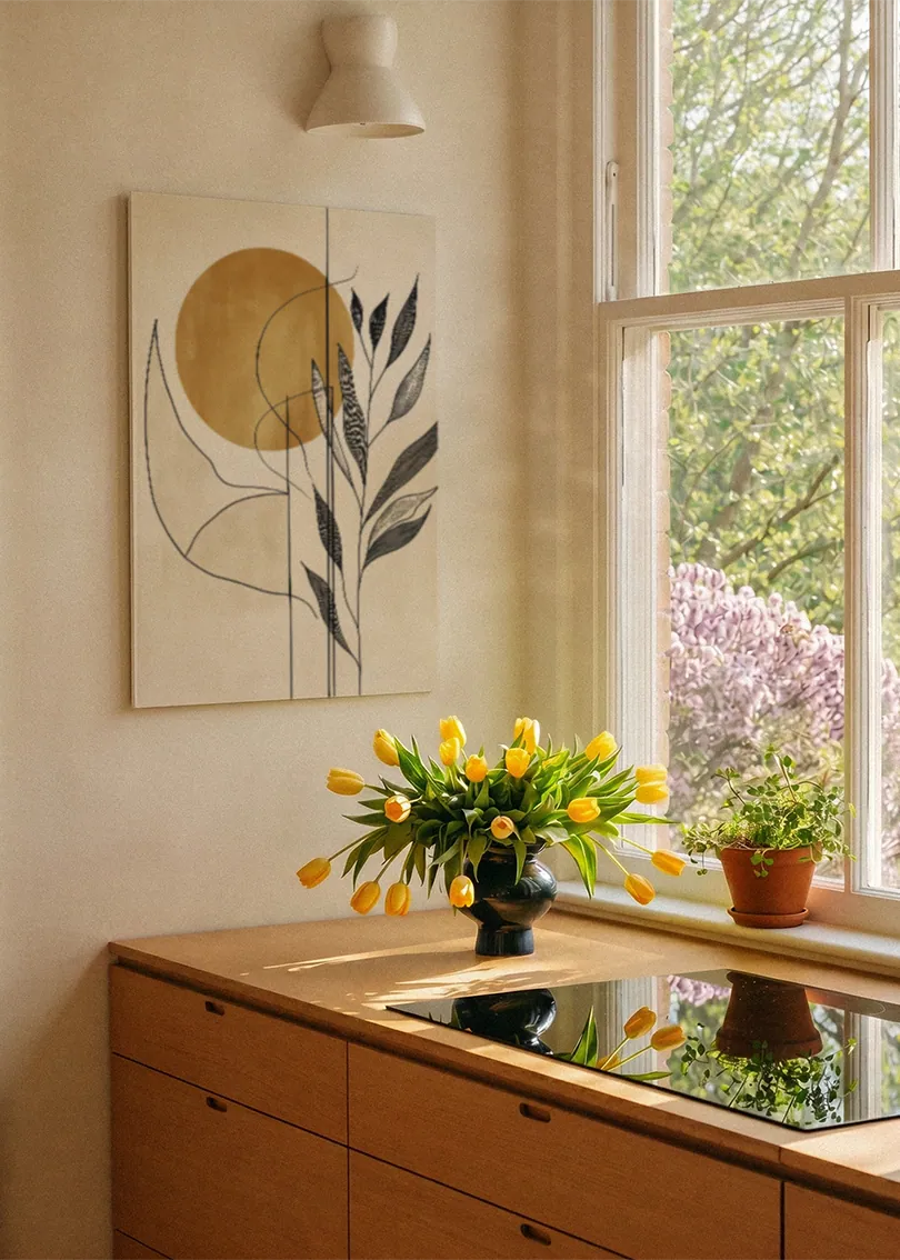 Akustikbillede med en gylden cirkel med grene i beige, ved et vindue med en blomsterbuket i karmen