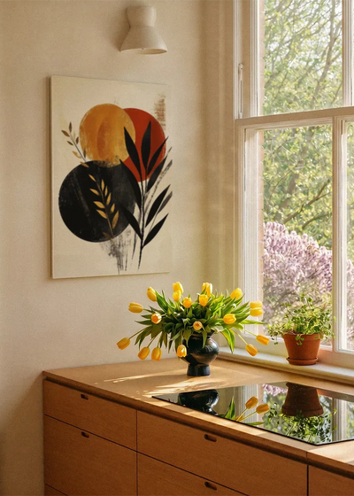 Akustikbillede med gyldne og sorte cirkler med blade, ved et vindue med en blomsterbuket i karmen
