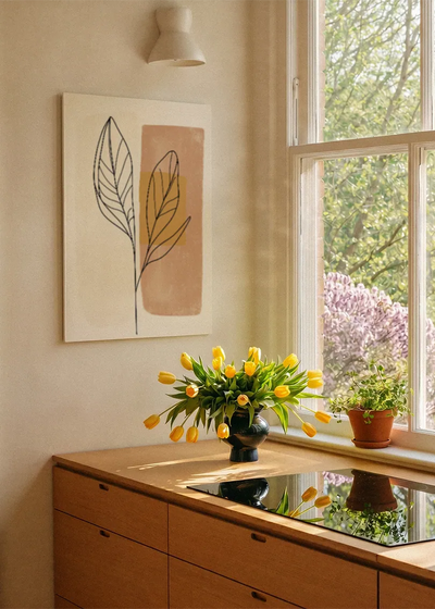 Akustikbillede med et gyldent blad på et terrakottafarvet felt, ved et vindue med en blomsterbuket i karmen