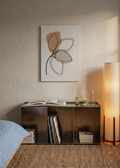 Akustikbillede med brune blade med tegnede konturer, over sengegavlen i et soveværelse med tændt lampe