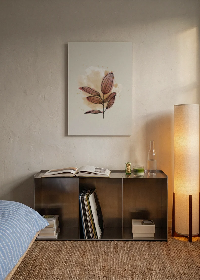 Akustikbillede med et brunt blad i akvarel, over sengegavlen i et soveværelse med tændt lampe