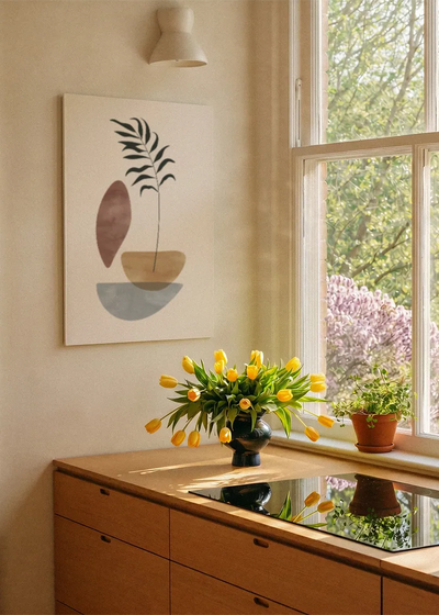 Akustikbillede med sorte grene i en skål med en brun form, ved et vindue med en blomsterbuket i karmen