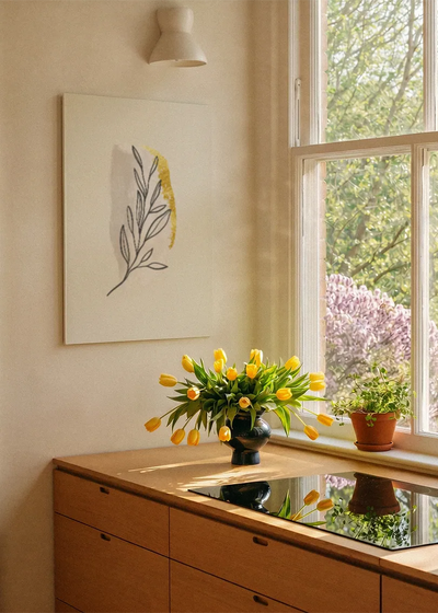 Akustikbillede med et gult blad med tegnede konturer, ved et vindue med en blomsterbuket i karmen