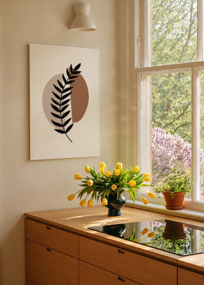 Akustikbillede med et sort bregneblad på en brun cirkel, ved et vindue med en blomsterbuket i karmen