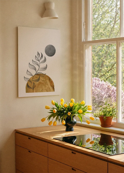 Akustikbillede med et hvidt bregneblad med gylden bakke og grå cirkel, ved et vindue med en blomsterbuket i karmen