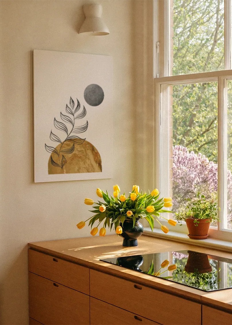Akustikbillede med et hvidt bregneblad med gylden bakke og grå cirkel, ved et vindue med en blomsterbuket i karmen