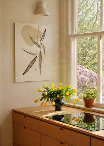 Akustikbillede med beige strå og blade, ved et vindue med en blomsterbuket i karmen