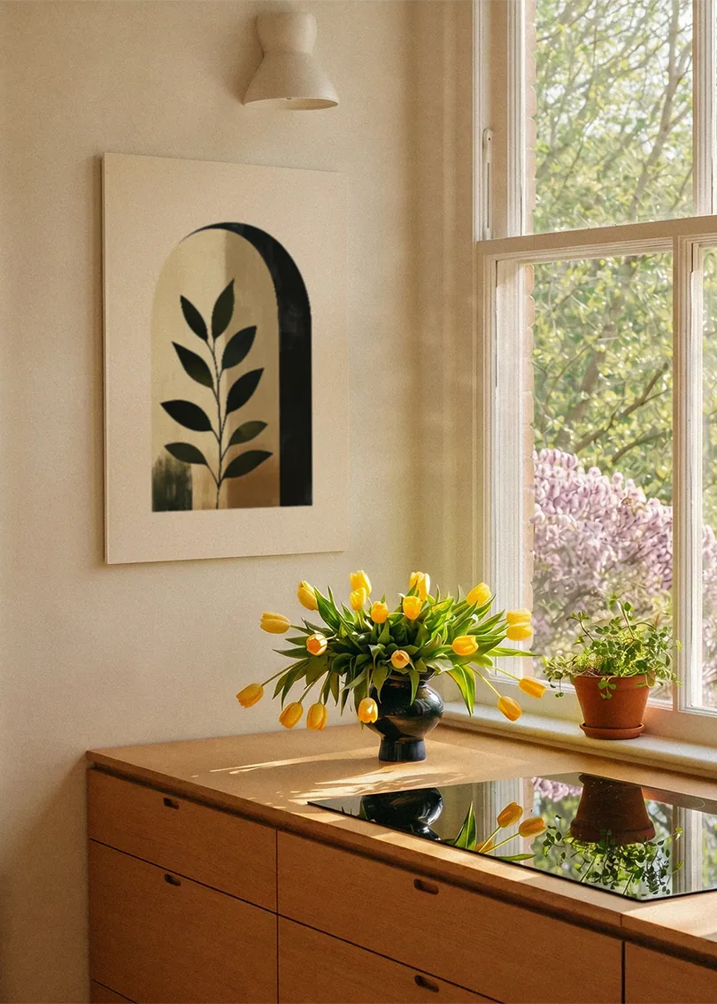 Akustikbillede med en bue med et grønt blad i beige toner, ved et vindue med en blomsterbuket i karmen
