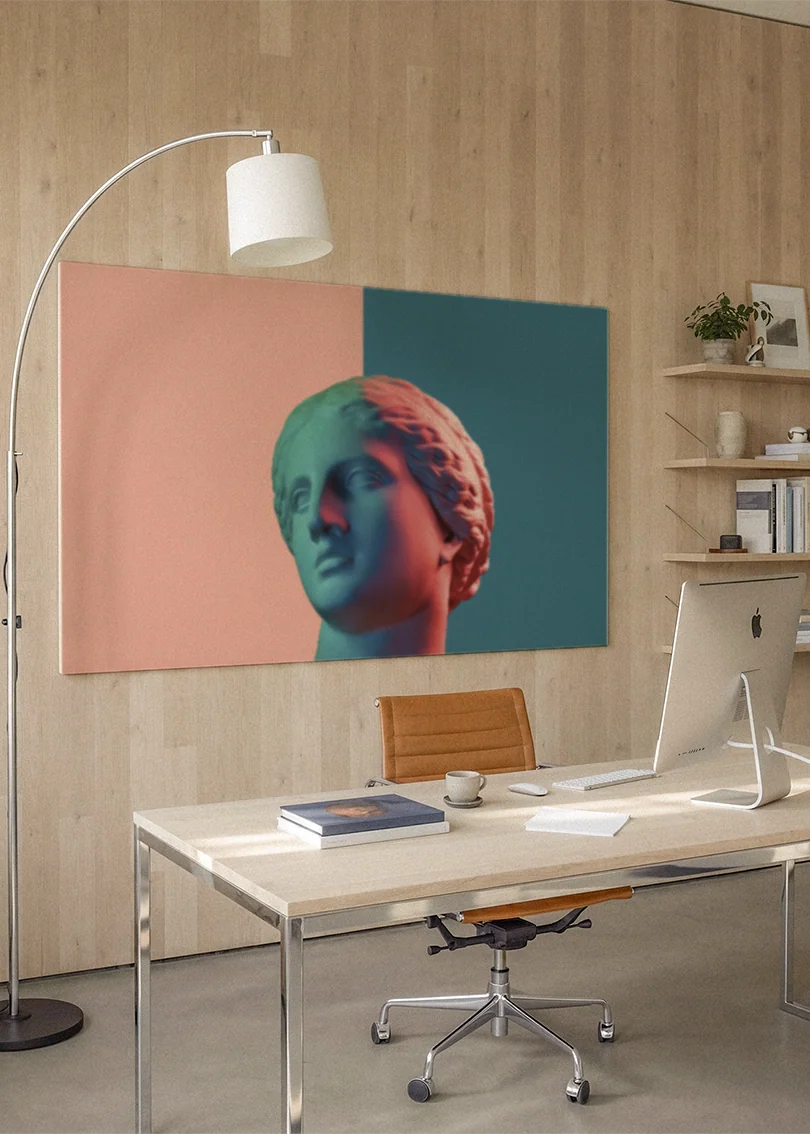 Akustikbillede med en gipsbuste delt i orange og blåt, på et hjemmekontor med hvidt skrivebord og buelampe