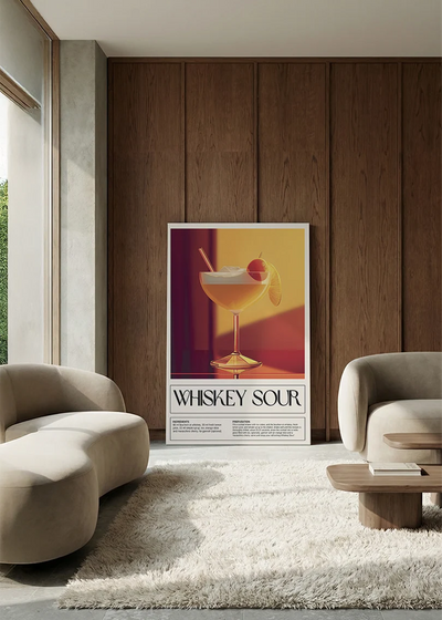 Akustikbillede med en retro cocktailplakat med Whiskey Sour, i en lounge med bugtet sofa mod vægpanel i valnød
