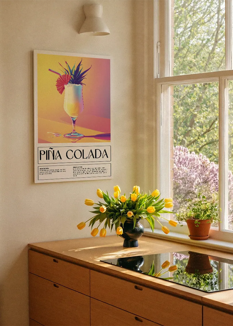 Akustikbillede med en retro cocktailplakat med Pina Colada, ved et køkkenvindue med gule tulipaner
