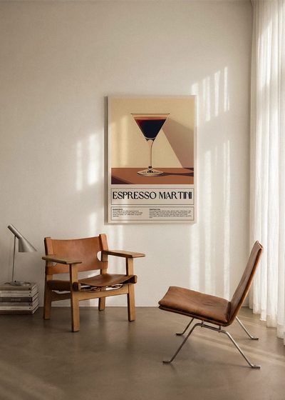 Akustikbillede med en retro cocktailplakat med Espresso Martini, ophængt over en lænestol ved gardinet
