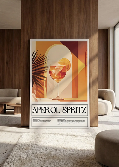 Akustikbillede med en retro cocktailplakat med Aperol Spritz, lænet mod vægpanel i valnød ved sofaen
