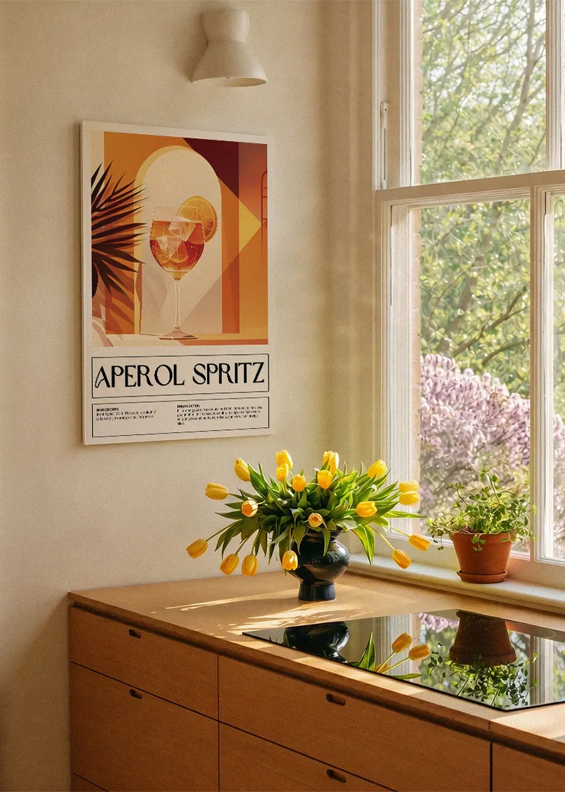 Akustikbillede med en retro cocktailplakat med Aperol Spritz, ved et køkkenvindue med gule tulipaner