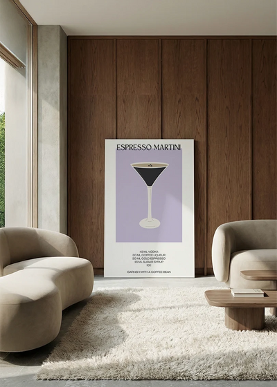 Akustikbillede med en minimalistisk cocktailplakat med Espresso Martini, i en lounge med bugtet sofa mod vægpanel i valnød