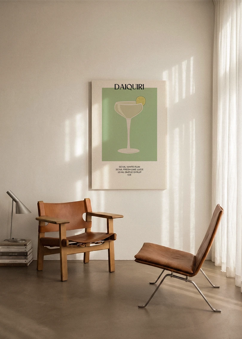 Akustikbillede med en minimalistisk cocktailplakat med Daiquiri, ophængt over en lænestol ved gardinet