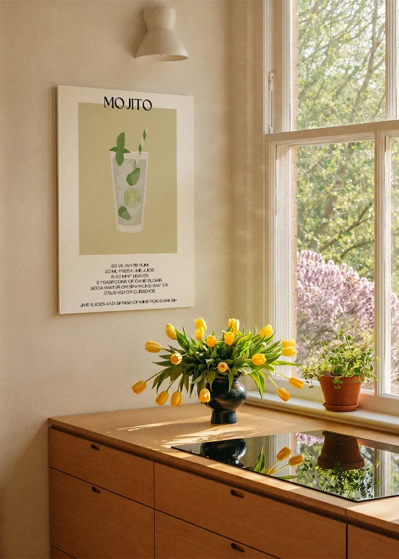Akustikbillede med en minimalistisk cocktailplakat med Mojito, ved et køkkenvindue med gule tulipaner
