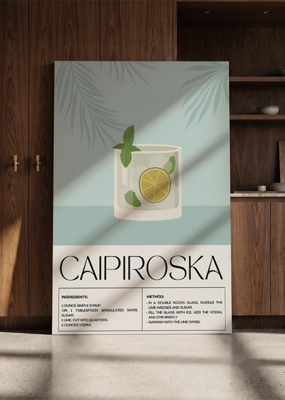 Akustikbillede med en retro cocktailplakat med Caipiroska, lænet mod en skabsvæg i valnød