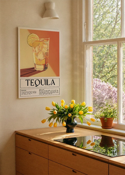 Akustikbillede med en retro cocktailplakat med Tequila, ved et køkkenvindue med gule tulipaner