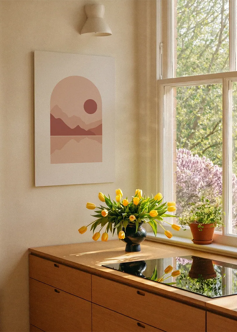 Akustikbillede med en rød sol over rosa bjerge, ved et vindue over køkkenbordet med gule tulipaner